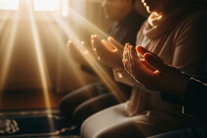 Close-up of hands extended in prayer position with golden sunlight streaming through, symbolizing spiritual devotion during Eid ul-Adha celebration, faith, and sacred connection